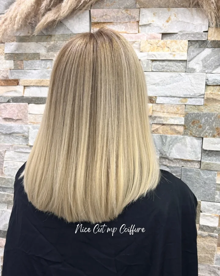 Après : carré blond beige lumineux, vu de dos devant le mur de pierre du salon